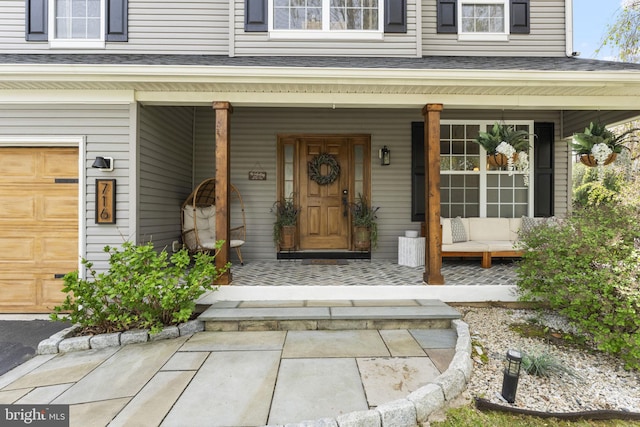 property entrance with an attached garage, a shingled roof, and covered porch