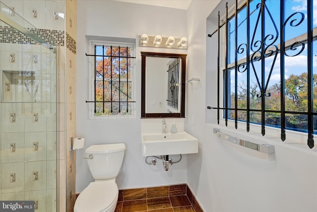 bathroom with baseboards, a stall shower, toilet, and a sink