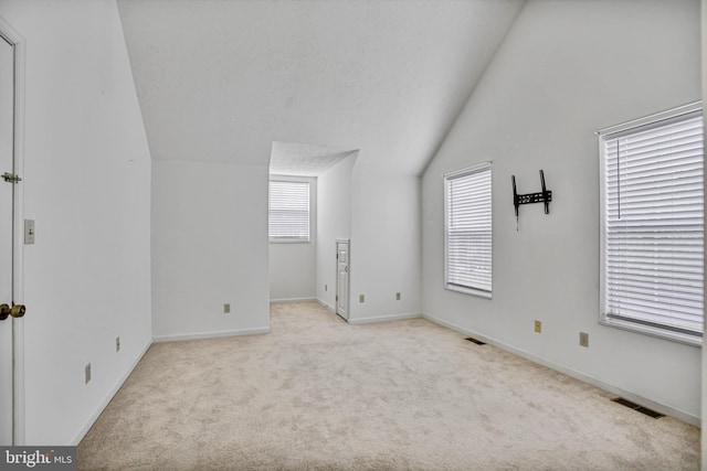 interior space featuring visible vents, lofted ceiling, a healthy amount of sunlight, and light colored carpet