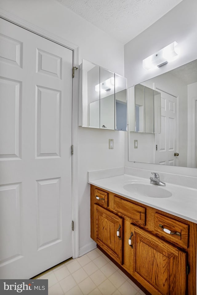 bathroom featuring vanity, a textured ceiling, and tile patterned flooring