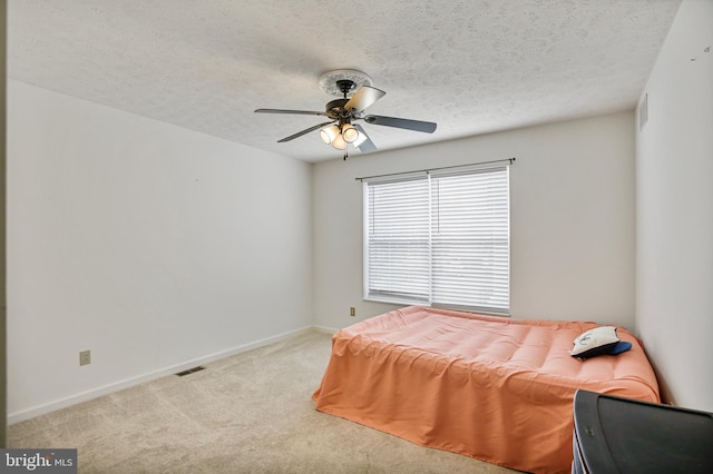 bedroom featuring visible vents, a ceiling fan, baseboards, a textured ceiling, and carpet flooring