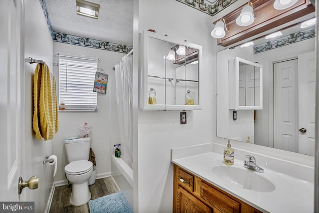 bathroom featuring a textured ceiling, wood finished floors, vanity, baseboards, and toilet