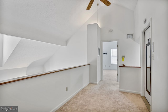 hall with visible vents, carpet flooring, baseboards, and high vaulted ceiling