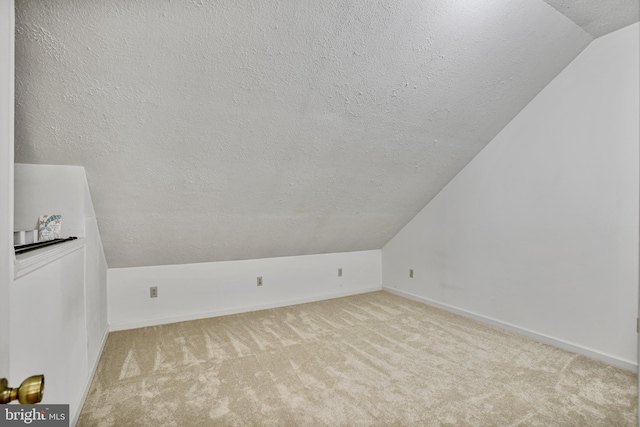 bonus room with carpet floors, a textured ceiling, baseboards, and vaulted ceiling