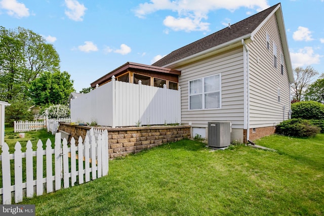 view of home's exterior with a yard, central AC, and fence