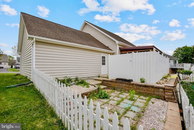 view of home's exterior with roof with shingles, a lawn, and a fenced backyard