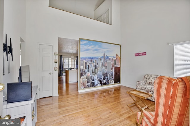 sitting room featuring a wealth of natural light, wood finished floors, and a towering ceiling