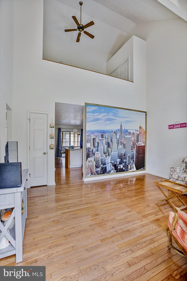 living area featuring light wood-style floors, high vaulted ceiling, and ceiling fan
