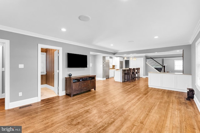 living room with an inviting chandelier, baseboards, light wood-type flooring, visible vents, and ornamental molding