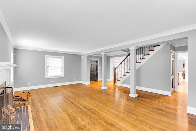 unfurnished living room featuring a fireplace with flush hearth, baseboards, ornamental molding, and light wood finished floors