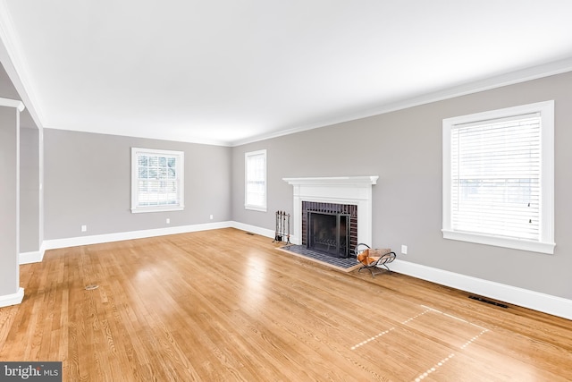 unfurnished living room with a brick fireplace, baseboards, and ornamental molding