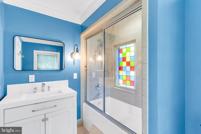 bathroom with baseboards, ornamental molding, shower / bath combination with glass door, and vanity