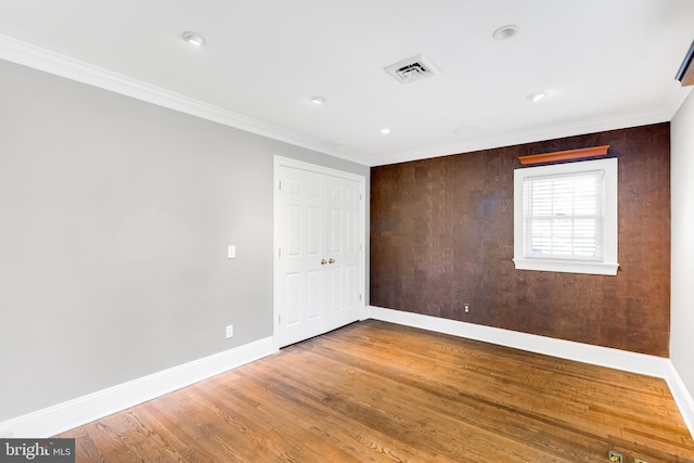 spare room featuring visible vents, crown molding, wood finished floors, baseboards, and recessed lighting