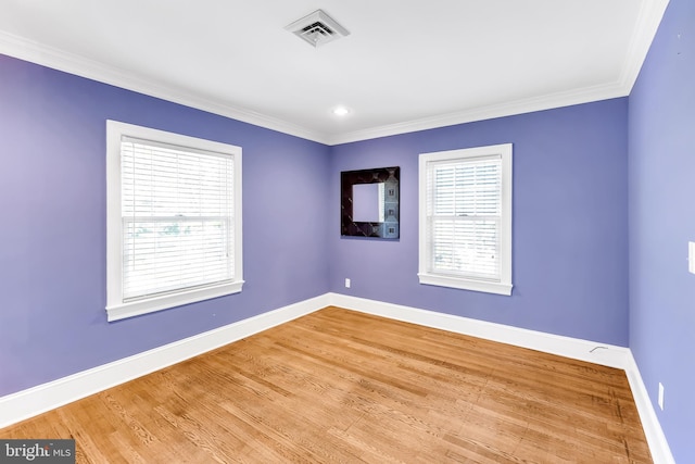 unfurnished room featuring baseboards, visible vents, ornamental molding, and wood finished floors