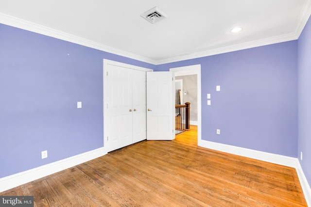 unfurnished bedroom featuring light wood finished floors, baseboards, visible vents, ornamental molding, and a closet