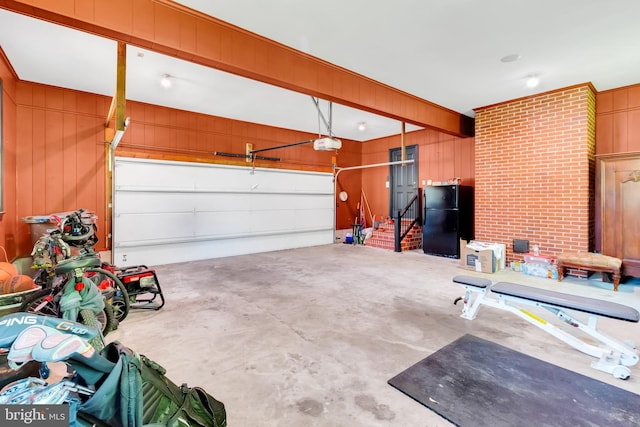 garage featuring wooden walls, a garage door opener, and freestanding refrigerator