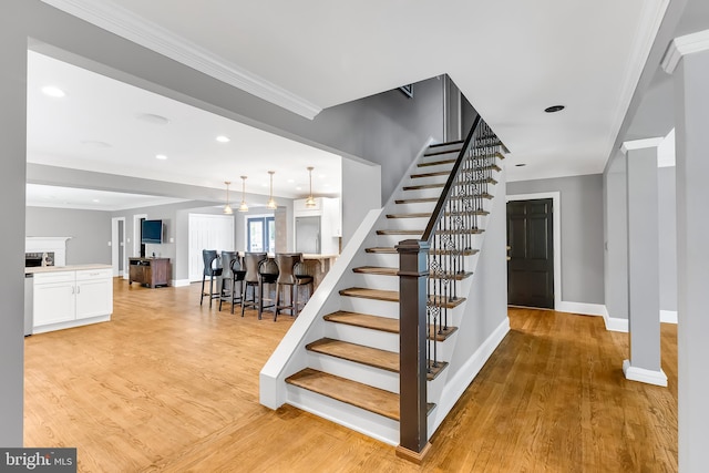 stairs with crown molding, baseboards, and wood finished floors
