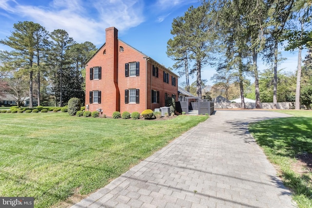 view of side of property with a lawn, fence, and a chimney