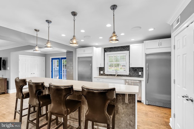 kitchen featuring appliances with stainless steel finishes, a sink, tasteful backsplash, visible vents, and ornamental molding
