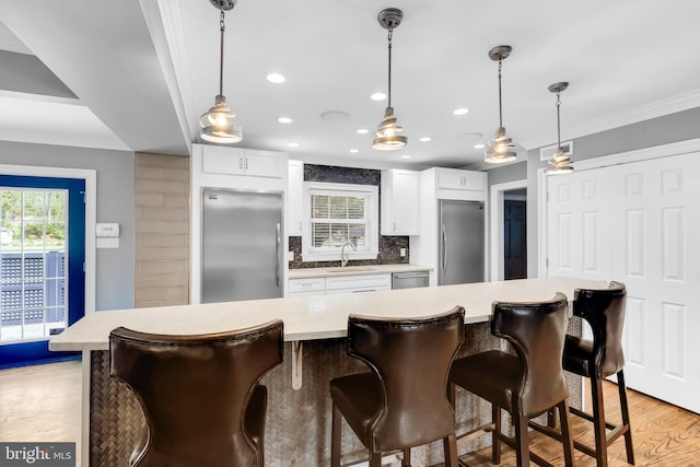 kitchen with ornamental molding, light countertops, tasteful backsplash, light wood-style flooring, and stainless steel appliances