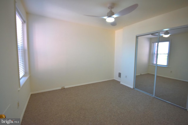 unfurnished bedroom with a closet, carpet flooring, ceiling fan, and visible vents