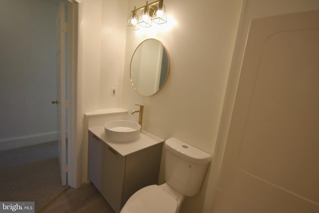 half bathroom featuring vanity, wood finished floors, and toilet