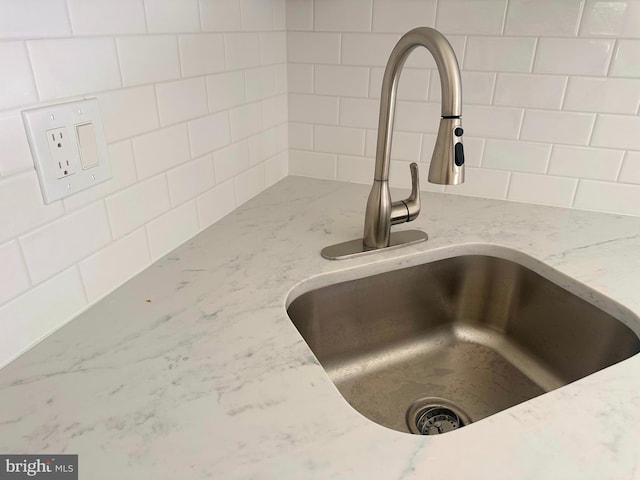 room details featuring a sink and light stone countertops
