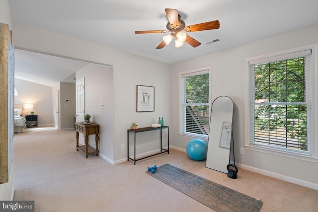 exercise room with baseboards, ceiling fan, light carpet, and visible vents