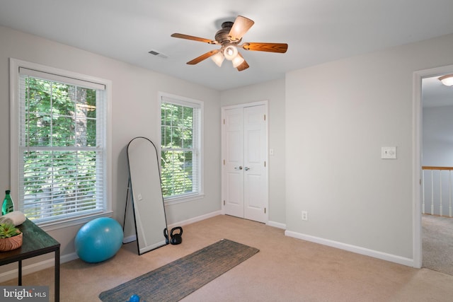 exercise room with light colored carpet, visible vents, baseboards, and ceiling fan