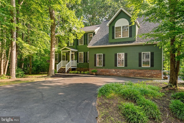 colonial house featuring driveway and a shingled roof