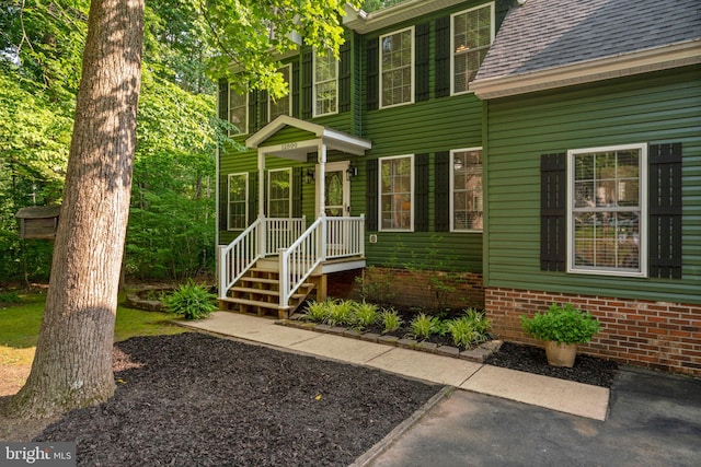 doorway to property featuring a shingled roof