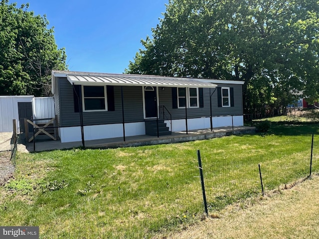 manufactured / mobile home featuring fence, metal roof, entry steps, and a front lawn