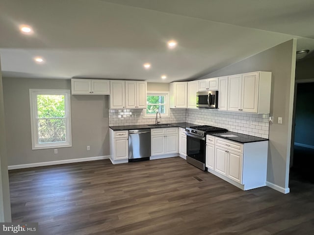 kitchen featuring a sink, appliances with stainless steel finishes, dark countertops, and tasteful backsplash