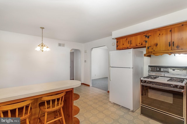 kitchen with gas stove, arched walkways, freestanding refrigerator, light floors, and visible vents