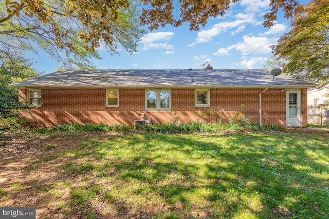 back of property with a chimney, a yard, and brick siding