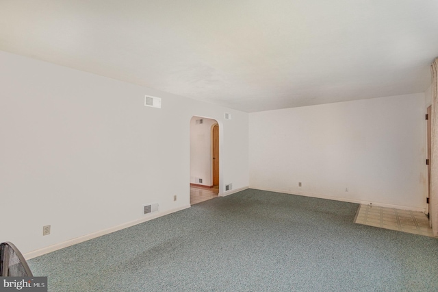 unfurnished room with arched walkways, carpet flooring, and visible vents
