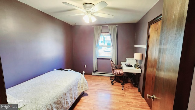 bedroom with light wood finished floors, ceiling fan, and a baseboard heating unit
