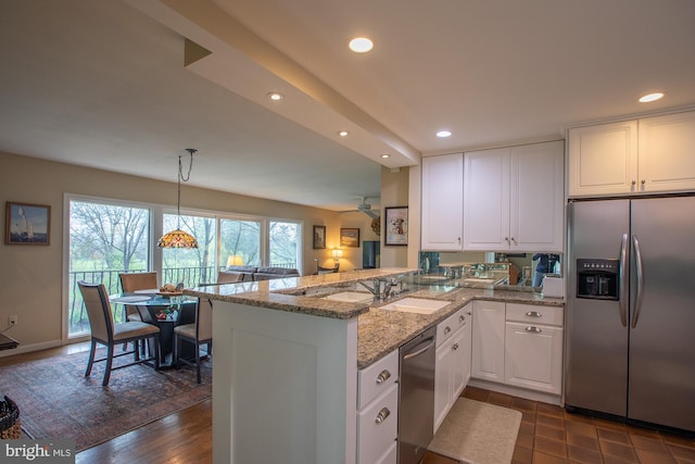 kitchen with appliances with stainless steel finishes, light stone counters, white cabinetry, recessed lighting, and a peninsula