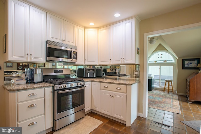 kitchen featuring baseboards, appliances with stainless steel finishes, white cabinets, and light stone countertops