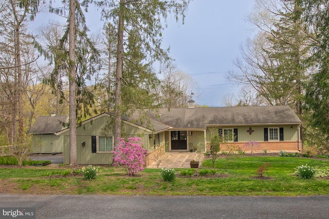 ranch-style house featuring a shingled roof, a chimney, and a front lawn
