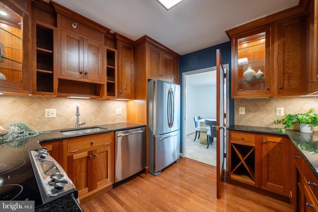 kitchen featuring open shelves, light wood-style floors, appliances with stainless steel finishes, brown cabinets, and a sink
