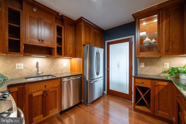 kitchen with appliances with stainless steel finishes, brown cabinets, light wood finished floors, and a sink