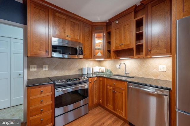 kitchen with open shelves, a sink, appliances with stainless steel finishes, and brown cabinetry
