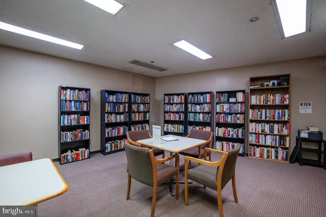 office area featuring wall of books and carpet floors