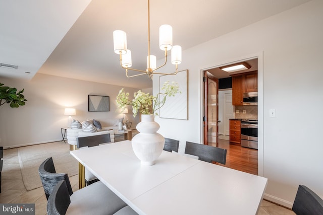 dining room featuring light tile patterned floors, visible vents, a notable chandelier, and baseboards