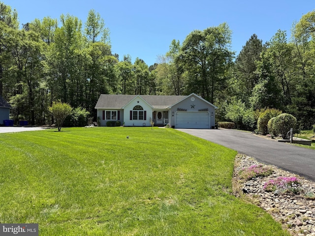 ranch-style house featuring a garage, a view of trees, driveway, and a front yard