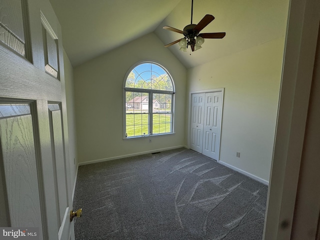 unfurnished bedroom with a ceiling fan, visible vents, vaulted ceiling, baseboards, and dark carpet