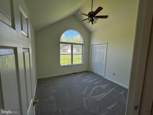unfurnished bedroom with baseboards, a ceiling fan, vaulted ceiling, and dark colored carpet