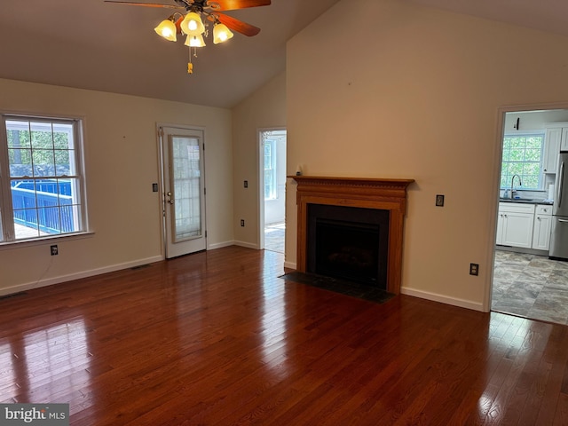 unfurnished living room with visible vents, a ceiling fan, a fireplace with flush hearth, wood finished floors, and a sink