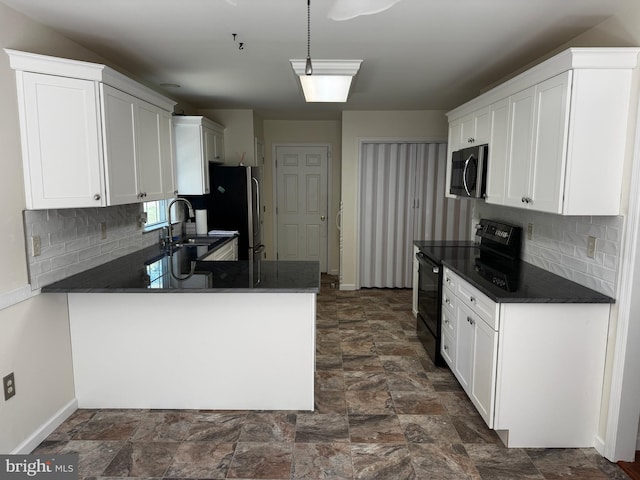 kitchen featuring dark countertops, a sink, stainless steel appliances, baseboards, and a peninsula